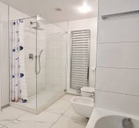 Badezimmer mit Badewanne, Dusche und Toilette in einer 3-Zimmer-Wohnung. Weiße Fliesen.