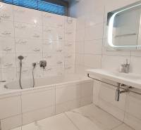 Badezimmer mit Badewanne und Fliesen in einer 3-Zimmer-Wohnung, weiße und graue Farbtöne.