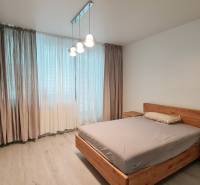 Schlafzimmer in einer 3-Zimmer-Wohnung, Holzmöbel, Boden mit Holzdekor, Vorhänge.