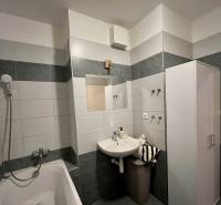 Badezimmer in einer 2-Zimmer-Wohnung mit Badewanne und Waschbecken mit Spiegel.