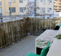 Der Balkon mit einem Rattanzaun und einem Tisch gehört zu einer 2-Zimmer-Wohnung.
