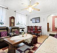 Wohnzimmer eines Einfamilienhauses mit Kamin, schwarzen Sofas und einem Boden in Holzoptik.