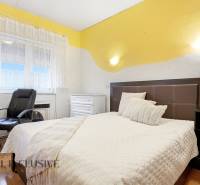 Schlafzimmer im Einfamilienhaus mit Bett, Sessel und Boden in Holzoptik.