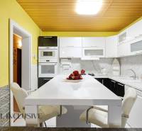 Küche mit weißer Arbeitsplatte, gelben Wänden und modernen Geräten in einem Einfamilienhaus.