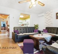 Wohnzimmer in einem Einfamilienhaus mit Holzboden und schwarzen Ledersofas.