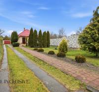 Zufahrtsweg und Garten rund um das Einfamilienhaus in Čierny Brod mit Nadelbäumen.