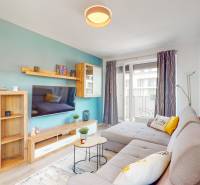 Wohnzimmer in einer 3-Zimmer-Wohnung mit einem bequemen Sofa und einem Balkon, Boden mit Holzdekor.