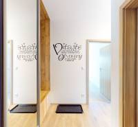 Eingangsflur mit Holzboden in einer 3-Zimmer-Wohnung und Schriftzug an der Wand.