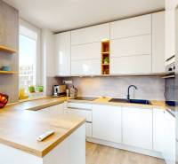 Küche in einer 3-Zimmer-Wohnung mit weißen Schränken, Holzboden und Theke.