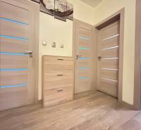 Holzboden-Dekor und helle Türen in einer 2-Zimmer-Wohnung mit sanfter Beleuchtung.