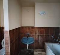 Badezimmer in einer 2-Zimmer-Wohnung mit Badewanne, Waschbecken und Toilette, gefliest.