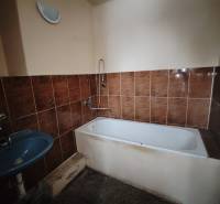 Badezimmer mit braunen Fliesen, Badewanne und blauem Waschbecken in einer 2-Zimmer-Wohnung.