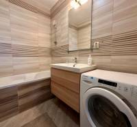 Badezimmer mit Badewanne, Waschbecken und Waschmaschine in einer 3-Zimmer-Wohnung.