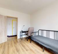 Ein Zimmer in einer 3-Zimmer-Wohnung mit einem Boden in Holzoptik, einem Schreibtisch und einem Bett.