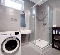 Badezimmer in einer 3-Zimmer-Wohnung mit Waschmaschine, Duschkabine und Waschbecken.