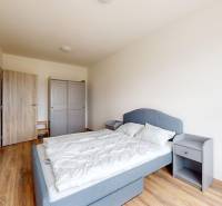 Schlafzimmer in einer 3-Zimmer-Wohnung mit Holzboden, grauem Bett und Kleiderschrank.