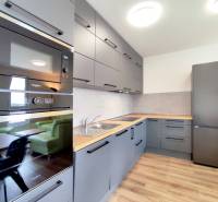 Küche in einer 3-Zimmer-Wohnung mit Holzboden, graue Schränke, Einbaugeräte.