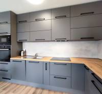 Eine stilvolle Küche in einer 3-Zimmer-Wohnung mit einem Holzboden und grauen Schränken.