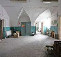 Innenraum eines Gebäudes mit gewölbter Decke und grauem Fliesenboden.