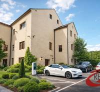 Ein Gebäude in Veľké Uherce mit Grünflächen und einer Ladestation für Elektroautos auf dem Parkplatz.