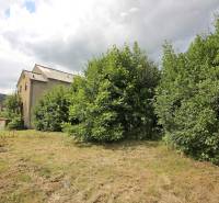 Ein Gebäude in Veľké Uherce, umgeben von Grün, mit Blick auf die hügelige Landschaft.