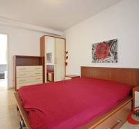 Schlafzimmer mit Holzboden, Bett, Schrank und Bild in einer 3-Zimmer-Wohnung.