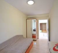 Ein Zimmer in einer 3-Zimmer-Wohnung mit einem Sofa, einem Einbauschrank und einem Boden mit Holzdekor.