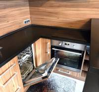 Küche in einer Einzimmerwohnung mit eingebautem Geschirrspüler und Holzelementen.