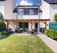 Garten und Terrasse bei einem Einfamilienhaus in Stupava mit gepflegtem Rasen und Blumenbeet.