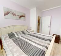 Schlafzimmer im Einfamilienhaus mit dekorativem Textil und Bodenbelag in Holzoptik.