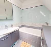 Ein Badezimmer mit Badewanne in einem Einfamilienhaus, elegante Accessoires und helle Farbtöne.