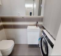 Badezimmer mit Toilette und Waschmaschine in einem Einfamilienhaus, helle Fliesen und Bodenbeläge.