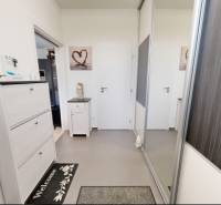 Innenraum eines Einfamilienhauses mit weißen Möbeln und einem Spiegelschrank. Stempel und Logo auf dem Bild.