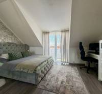 Schlafzimmer in einer 2-Zimmer-Wohnung mit Doppelbett, Schreibtisch und Boden mit Holzdekor.