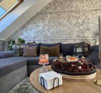 Wohnzimmer in einer Zweizimmerwohnung mit dekorativen Kissen auf dem Sofa und Kerzen auf dem Tisch.