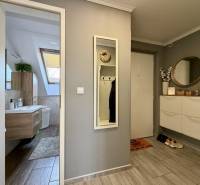 Flur mit Holzboden, Spiegel und Badezimmer in einer 2-Zimmer-Wohnung.