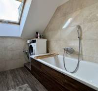 Badezimmer mit Dachfenster, Waschmaschine und Boden mit Holzdekor in einer 2-Zimmer-Wohnung.