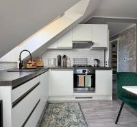 Küche in einer 2-Zimmer-Wohnung mit schräger Decke und Holzboden.