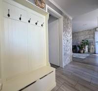 Eingangsflur in einer 2-Zimmer-Wohnung mit Kleiderhaken, der in das Wohnzimmer mit Pflanzen führt.