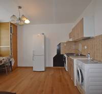 Küche in einer Einzimmerwohnung mit Holzboden, Esstisch und Geräten.