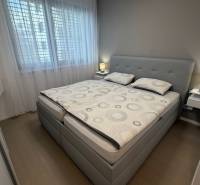 Schlafzimmer in einer 2-Zimmer-Wohnung mit Bett, Nachttischen und Boden mit Holzdekor.