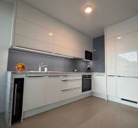 Moderne Küche in einer Zweizimmerwohnung mit Holzboden und weißen Schränken.