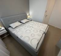 Schlafzimmer mit Doppelbett und Holzboden in einer Zweizimmerwohnung.