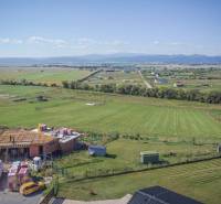 Grundstücke - Wohnen in Mlynica mit Blick auf ein im Bau befindliches Gebäude und Naturszenerie.