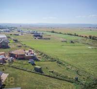 Grundstücke - Wohnen in Mlynica; im Bau befindliche Häuser und ausgedehnte Felder unter sonnigem Himmel.