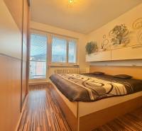 Schlafzimmer in einer 4-Zimmer-Wohnung mit Bett, Einbauschrank und Boden in Holzoptik.