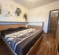 Schlafzimmer mit Einbauschränken und Bett in einer 4-Zimmer-Wohnung mit Holzdekor.