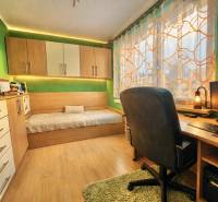 Ein Zimmer in einer 4-Zimmer-Wohnung mit einem Schreibtisch, einem Bett und einem Boden in Holzoptik.