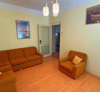 Wohnzimmer in einem Einfamilienhaus mit orangefarbenen Möbeln und einem Boden in Holzoptik.