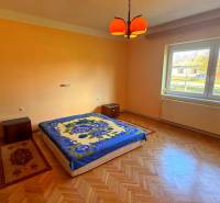 Ein Schlafzimmer in einem Einfamilienhaus mit einem Boden in Holzoptik und orangefarbenen Wänden.